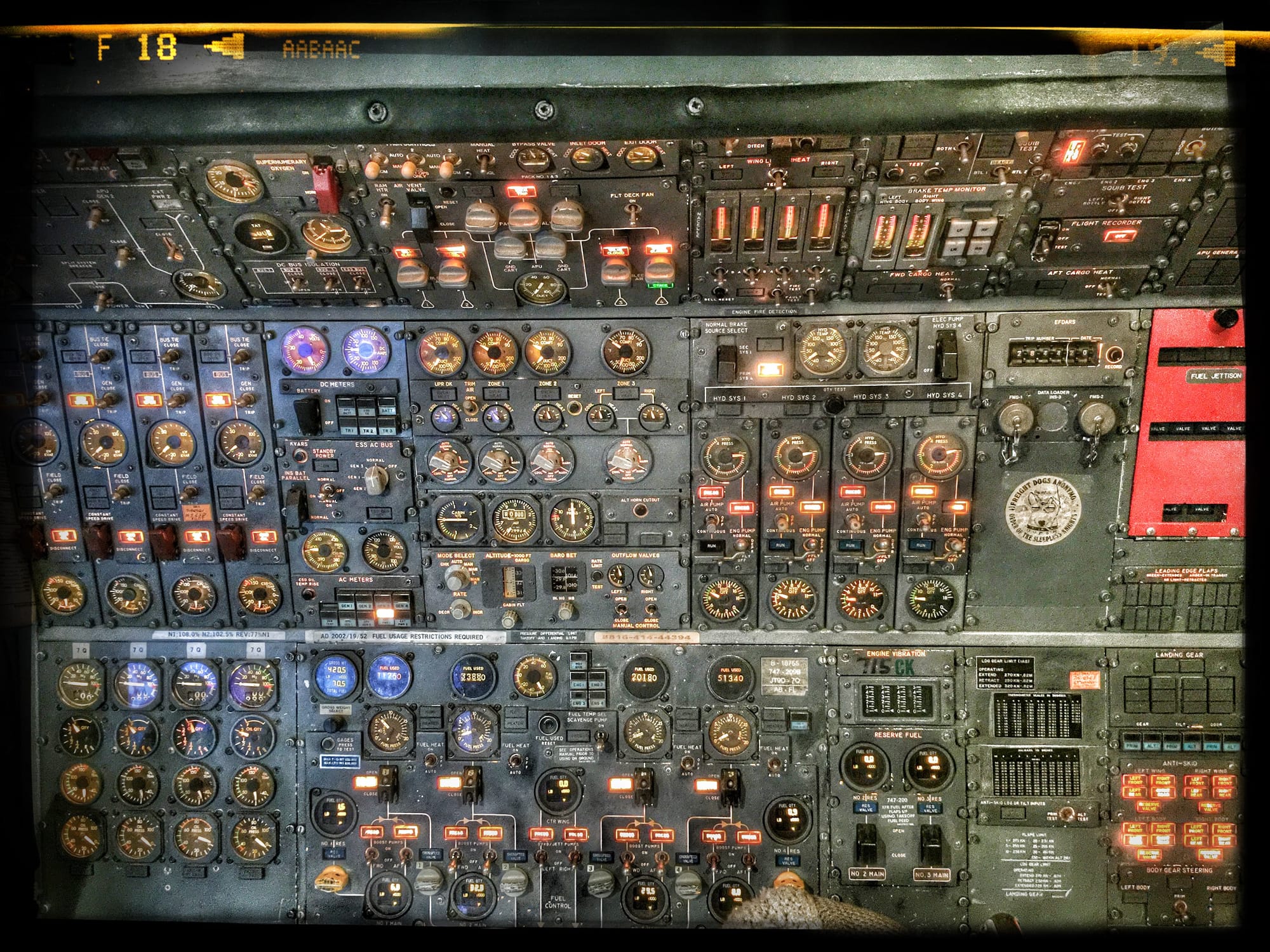 Hundreds of gauges, switches, buttons, and knobs fill one small part of an airplane cockpit. The panel is full of active lights on a deep military green metal.