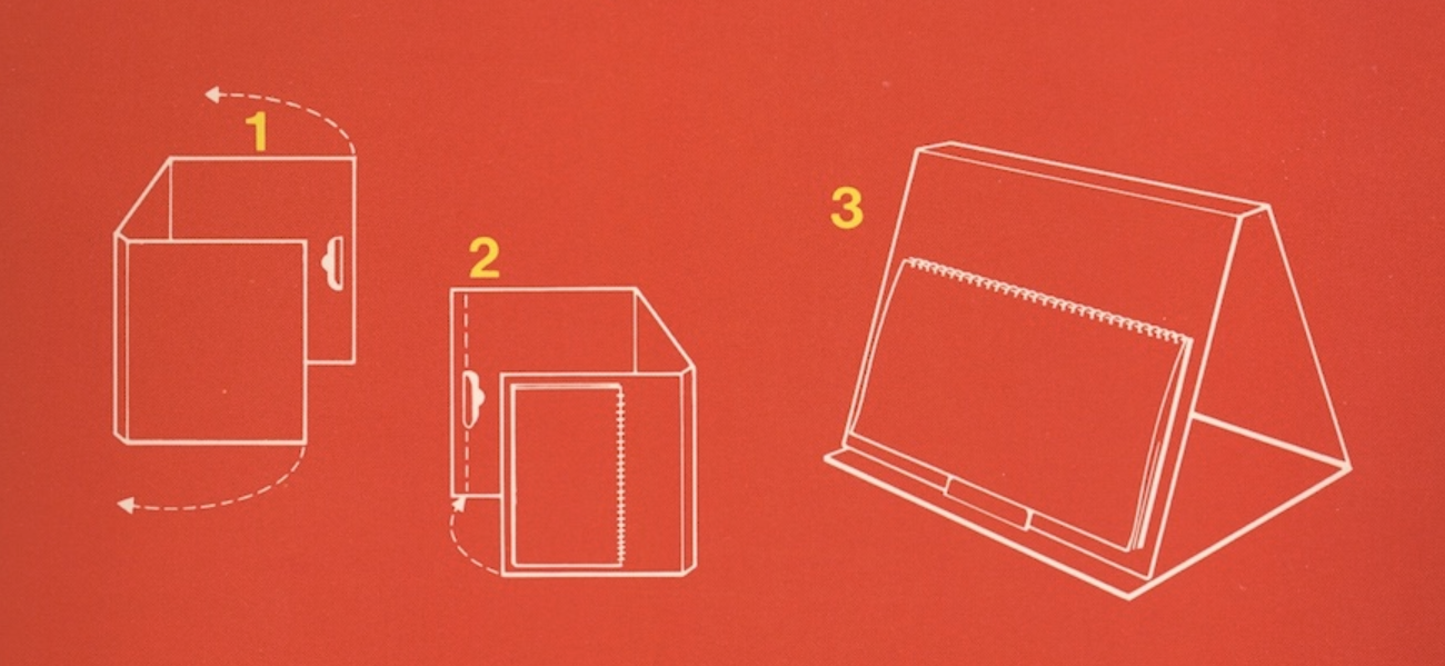 Scan from one of the manuals for PaperClip that could be folded into a kickstand to hold the lengthwise bound manual. The instructions show how to fold the box, or maybe some auxiliary cardboard shipped with it in three easy steps.
