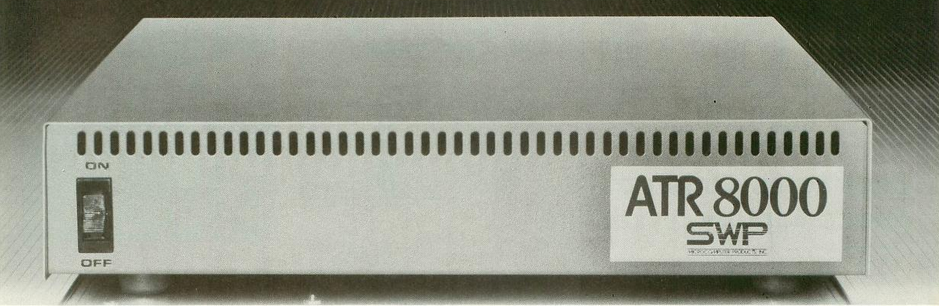 What is it with CP/M boxes being so boring looking? This is an image of the ATR8000 from a black and white magazine advertisement. It is a simple light grey box with an on/off toggle switch on the front left. On the right, a nameplace reads "ATR8000 SWP". Ventilation holes run along the top edge of the face plate.